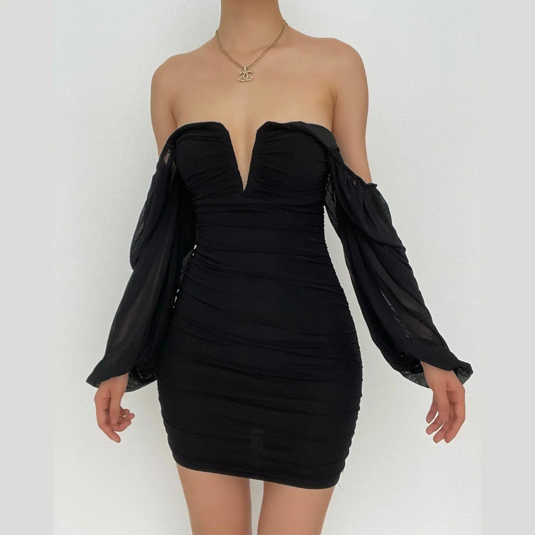 Back view of a black bodycon mini dress with ruched details and long sheer sleeves.