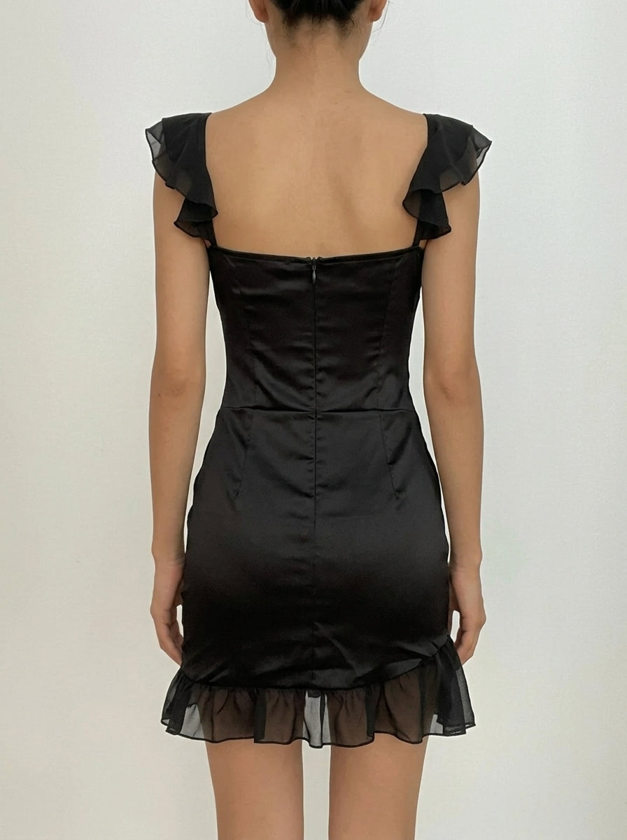 Back view of a model in a black sweetheart corset mini dress, showing ruffled cap sleeves.