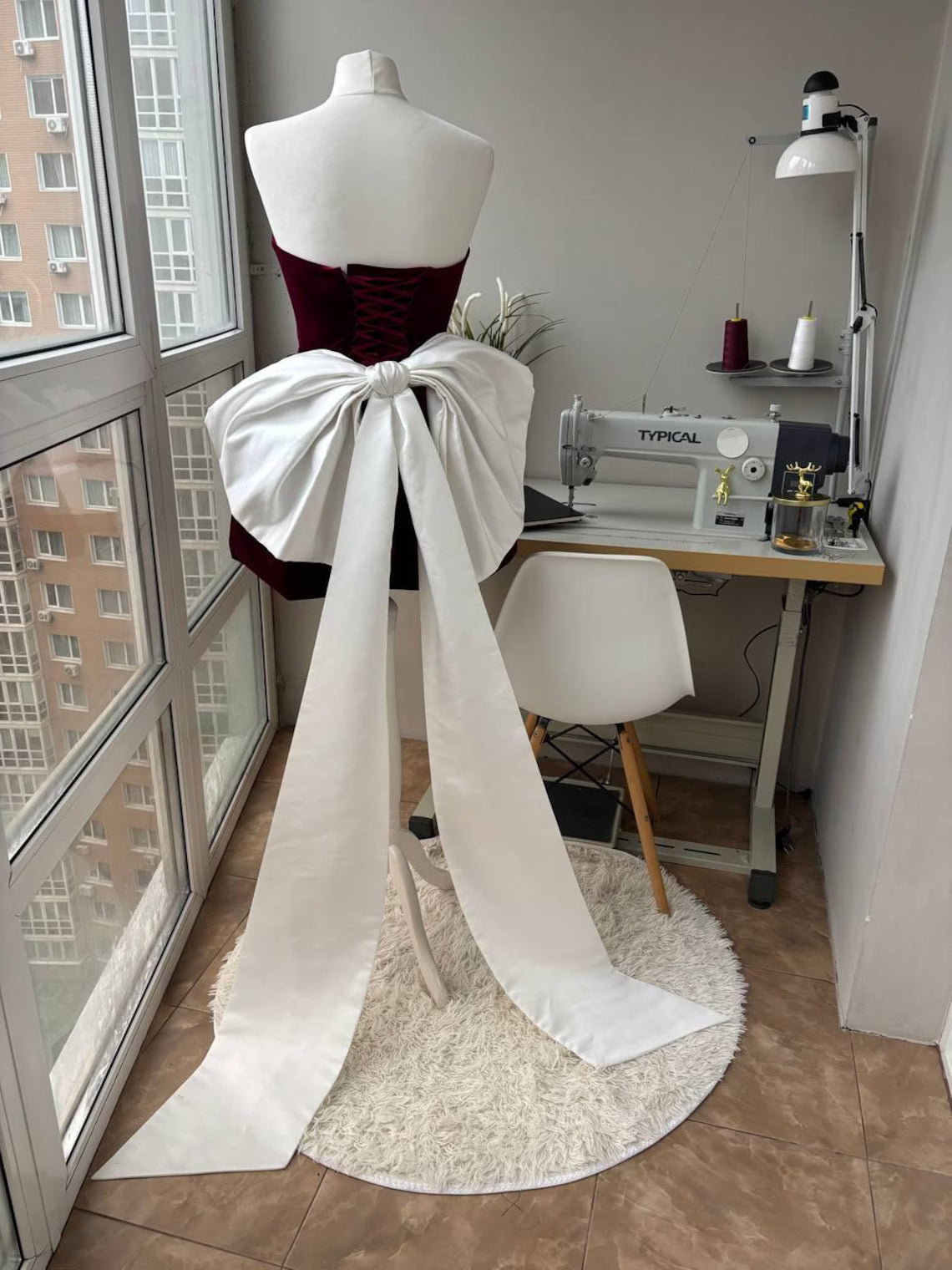 Back view of the burgundy velvet homecoming dress, showcasing the large white bow and corset lacing.