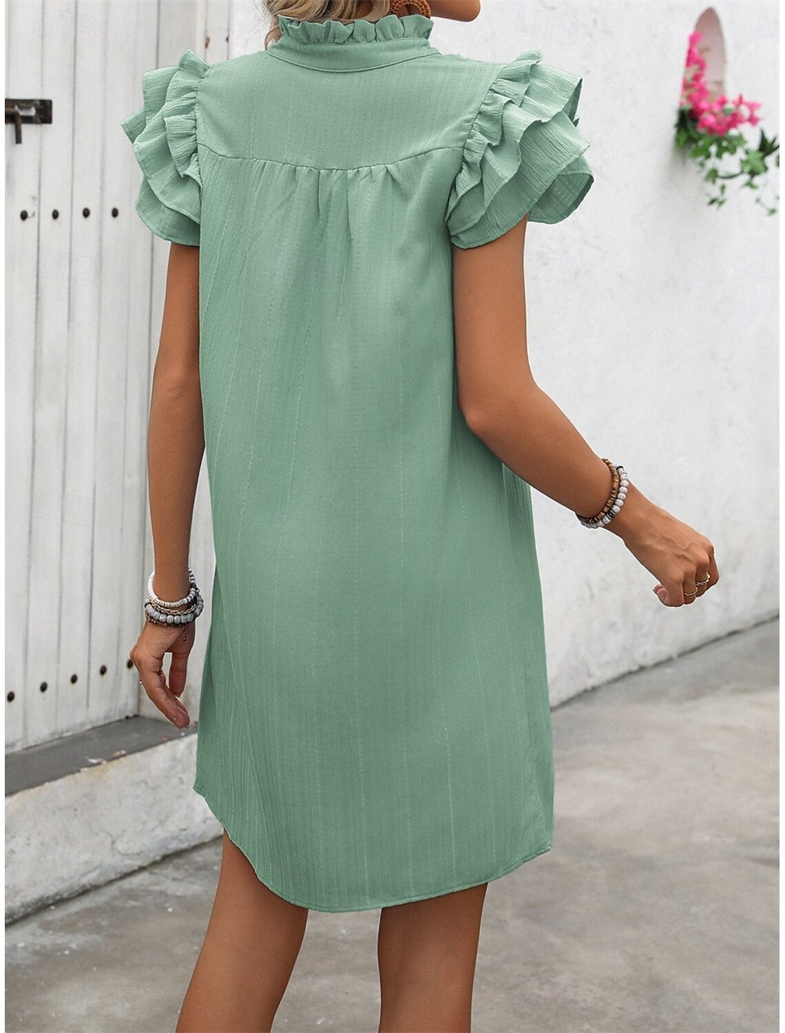 Woman in a plain A-line V-neck mini dress, side profile.