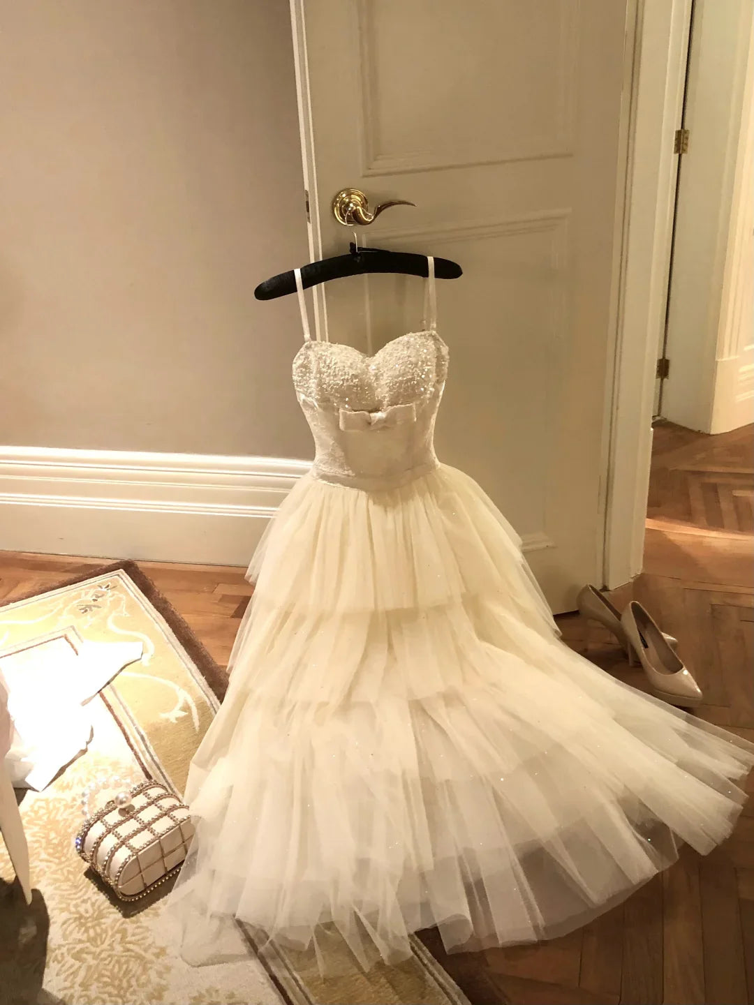 Model wearing a white A-line spaghetti strap dress with beaded bodice and layered tulle skirt.
