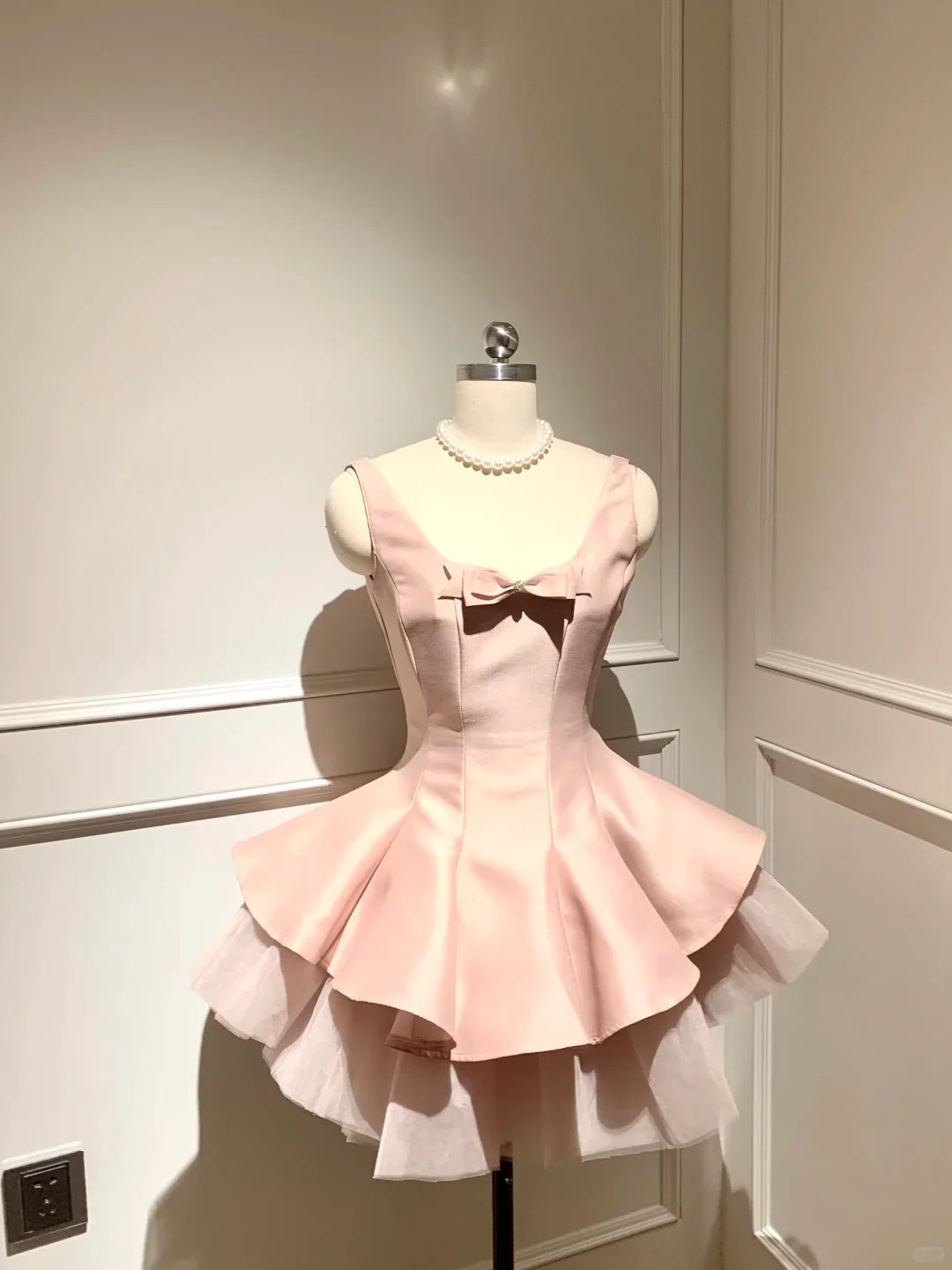 Light pink A-line homecoming dress with bow detail and spaghetti straps.