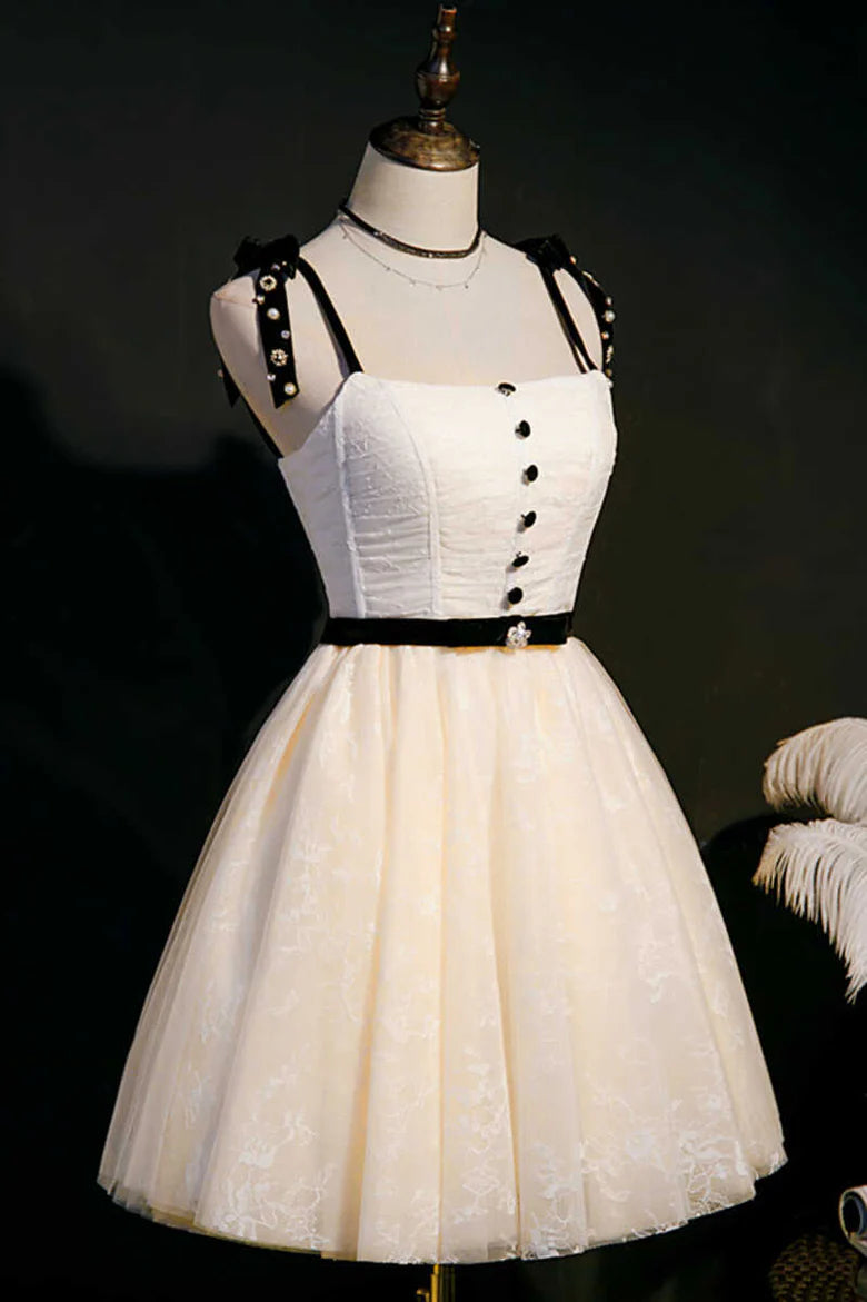 Close-up of the bow straps and black waist sash on the beige homecoming dress.