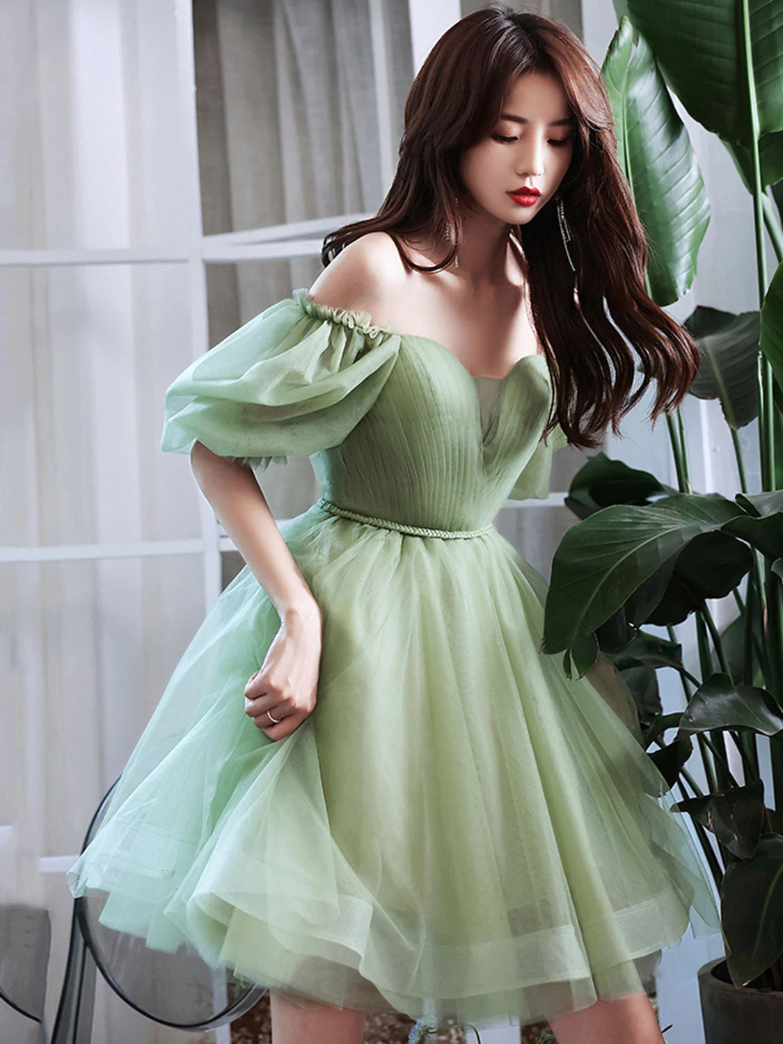 Front view of a woman wearing a chic A-line green tulle short prom dress.