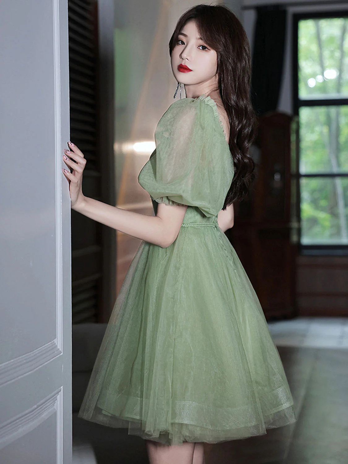 Side view of a woman in a green tulle short homecoming dress, highlighting the fitted waist.