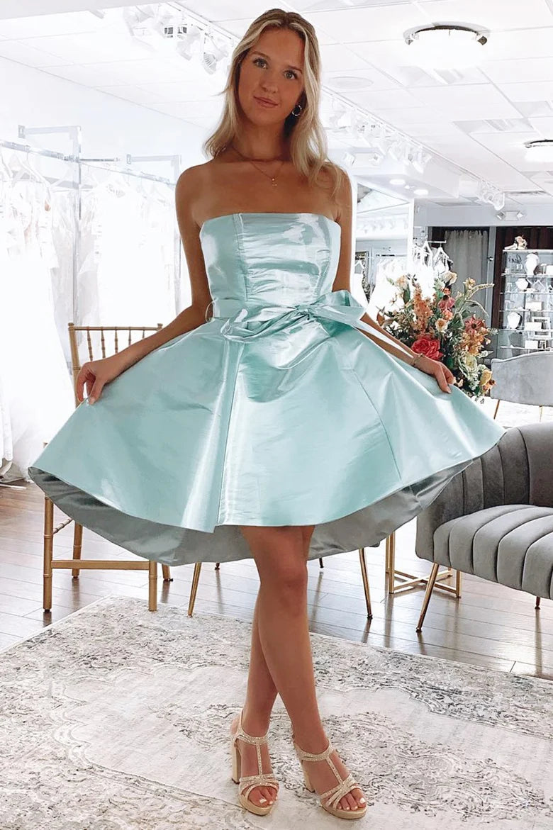 Front view of a woman wearing a mint green off-shoulder A-line high-low party dress with a tie-front detail.