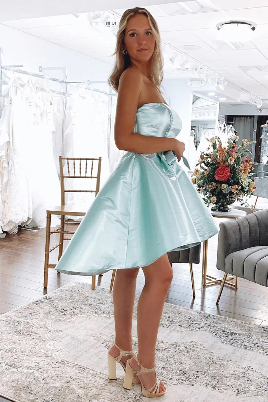 Side and back view of a woman in a mint green off-shoulder high-low party dress, showcasing the flowing hem.