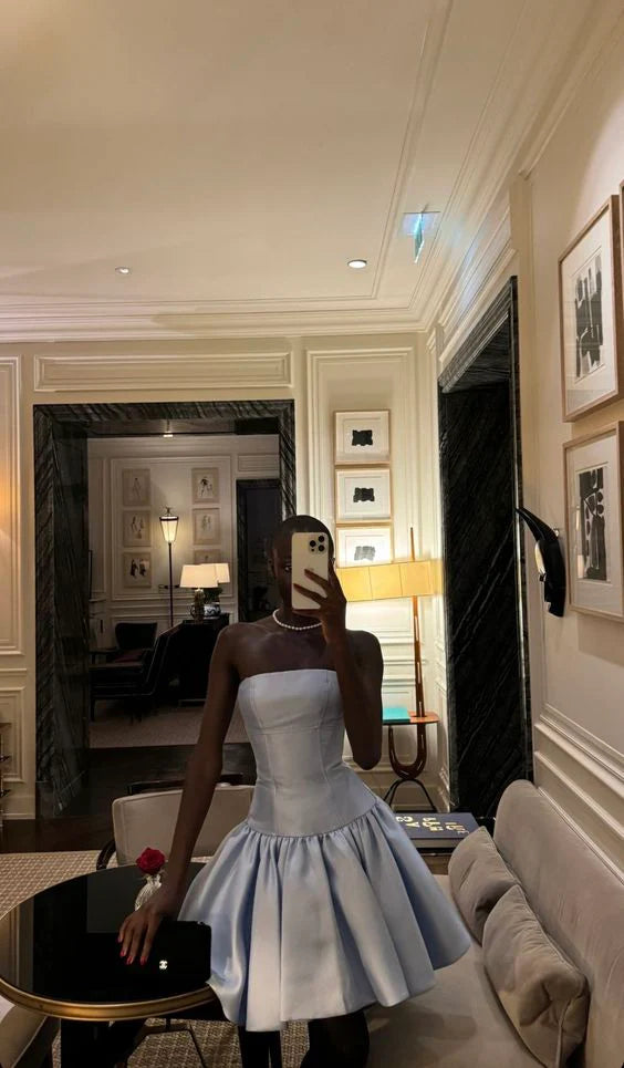 Woman posing in a light blue strapless A-line ruffled short party dress.
