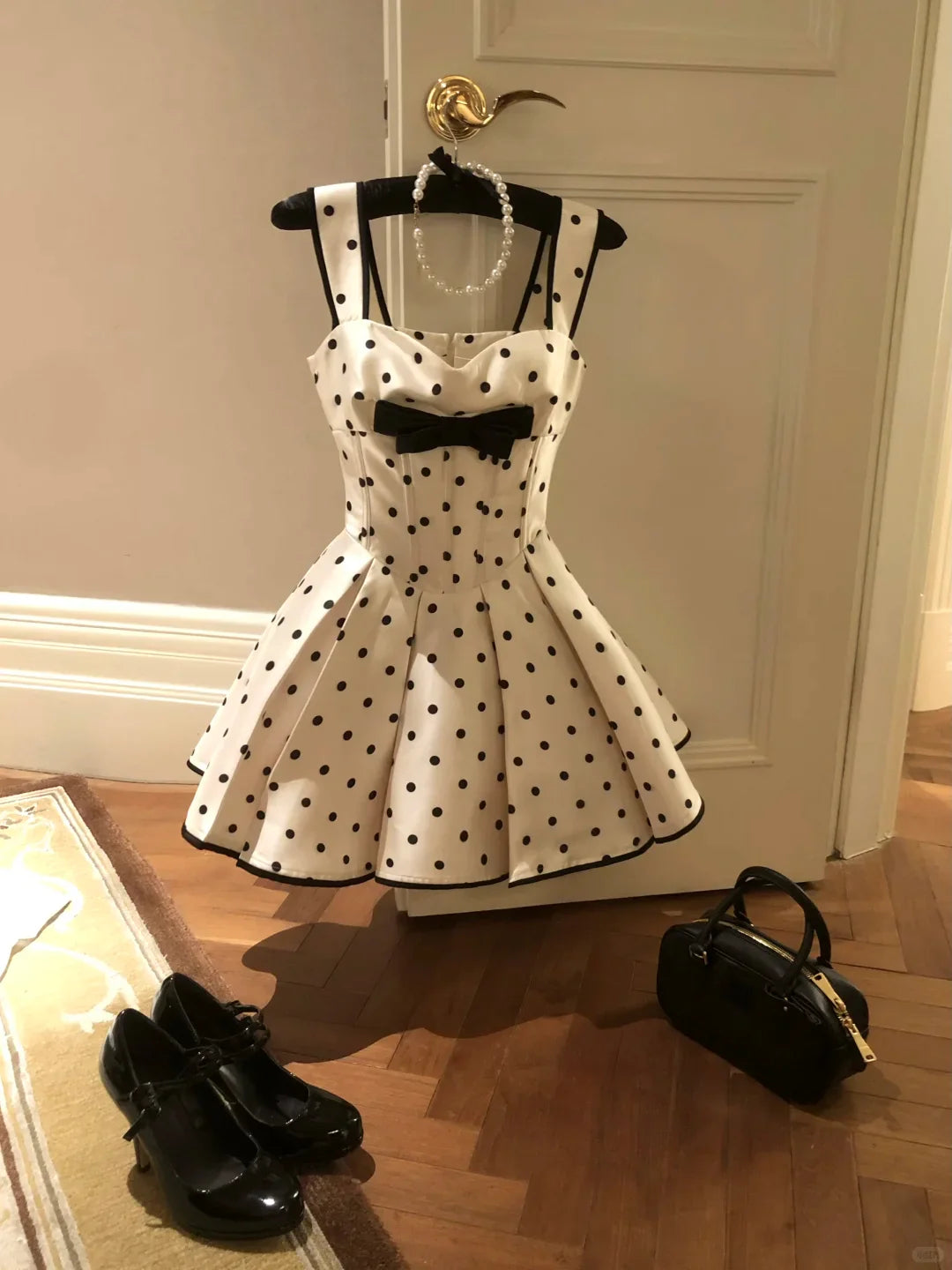 Model wearing a white polka dot A-line homecoming dress with a bow.