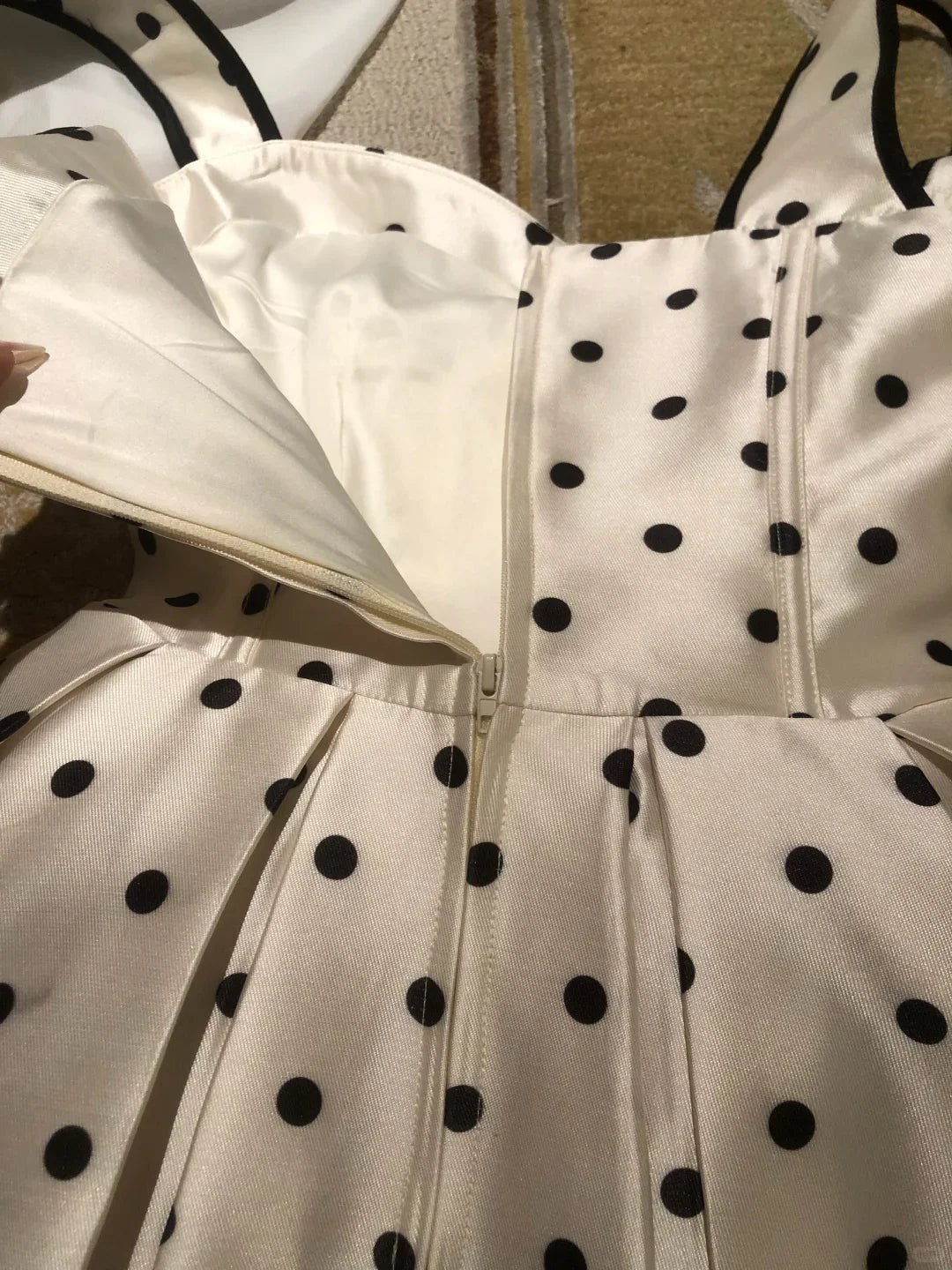 Back view of a white polka dot short dress with spaghetti straps.