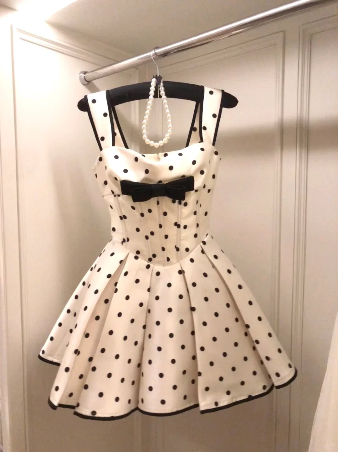 Side profile of a woman in a retro white A-line dress with a bow.