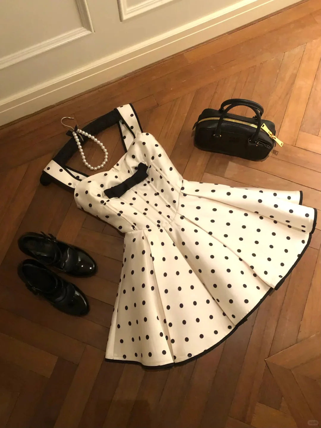 Close-up of the sweetheart neckline and bow detail on a white polka dot dress.