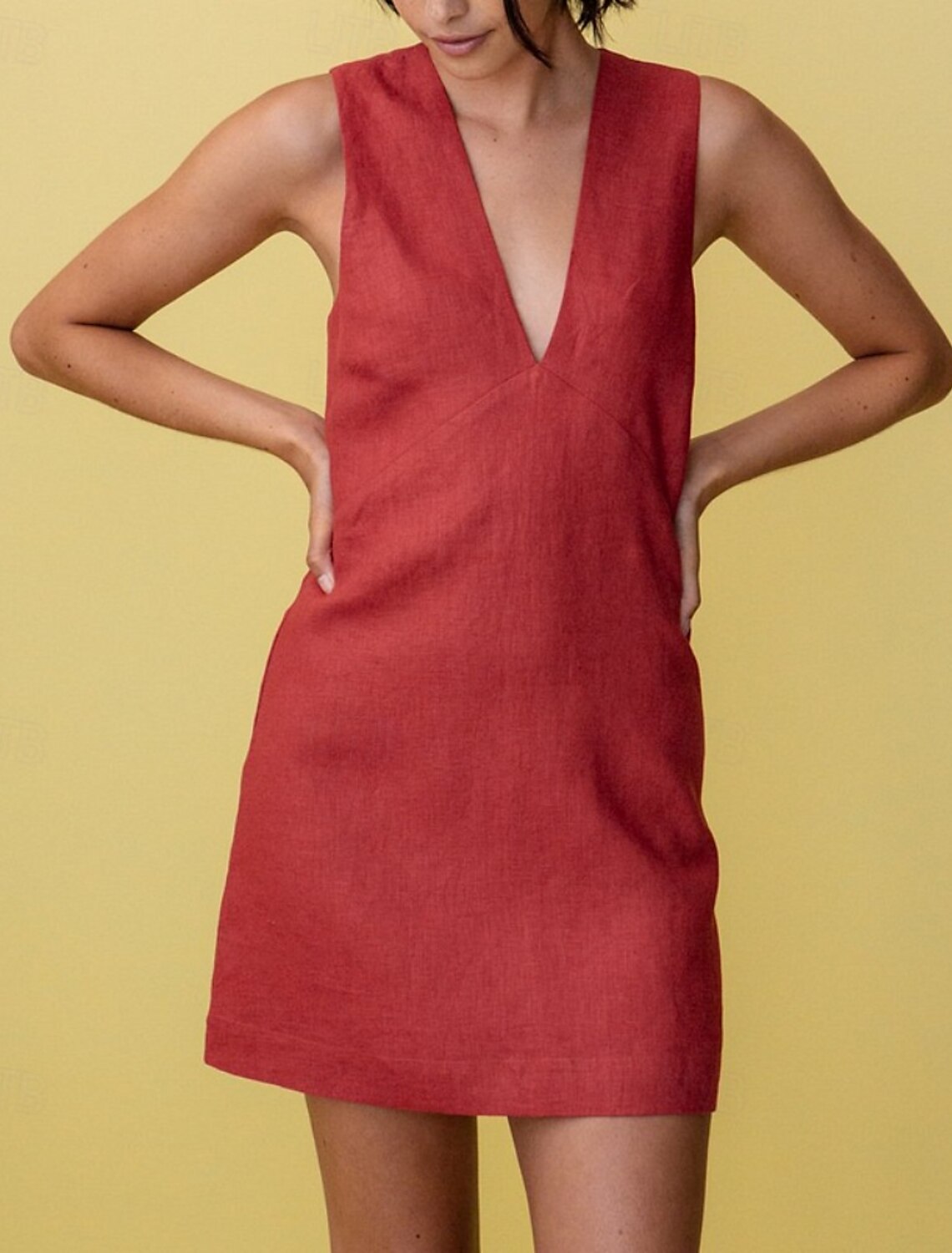 Woman posing in a pure color A-line V-neck sleeveless mini dress, side view.