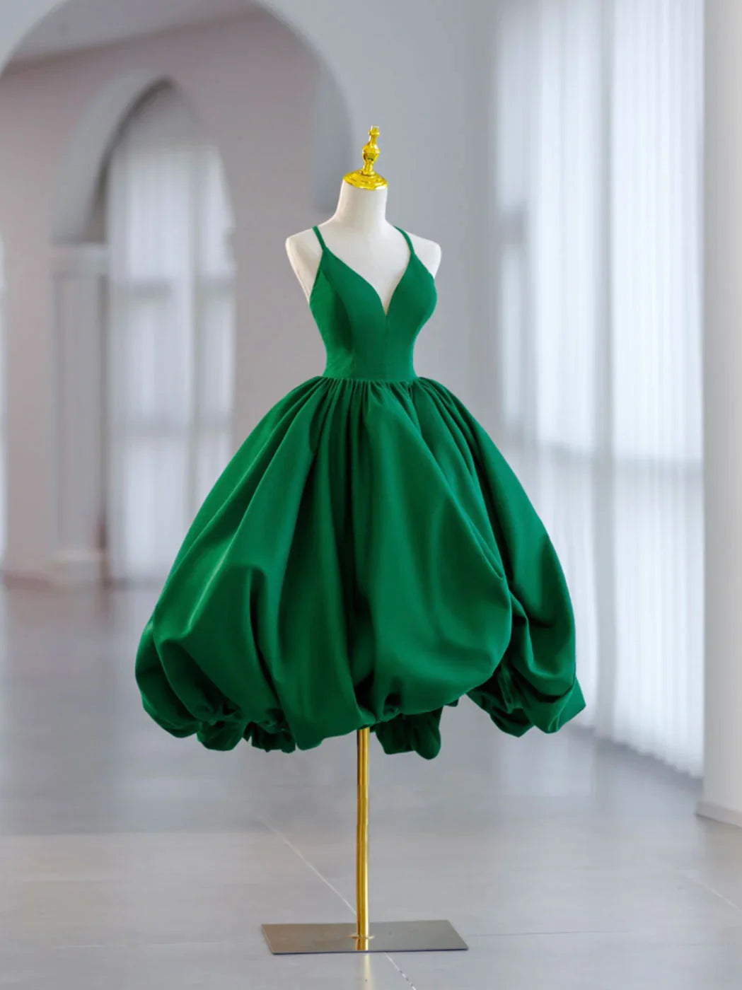 Front view of a model wearing a short green satin ball gown prom dress.