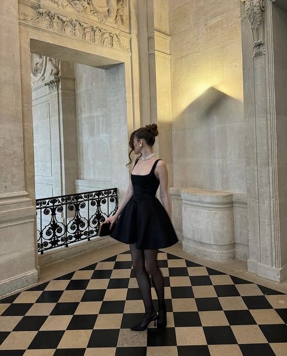 Woman posing in a chic black square neck bodycon mini party dress.