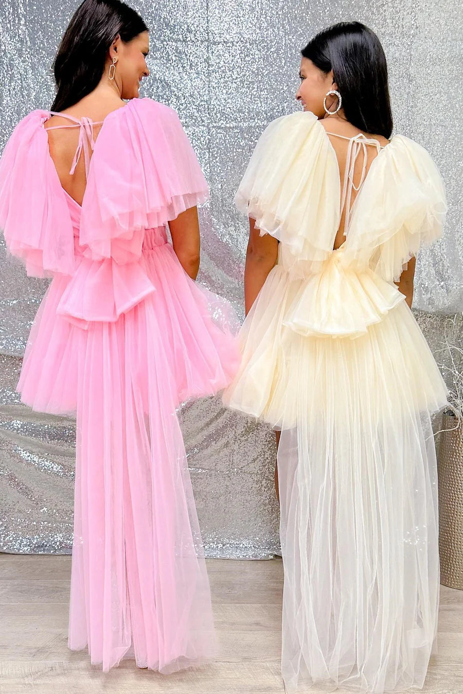 Back view of a model wearing a pink plunge V A-line homecoming dress with a bow and attached train.