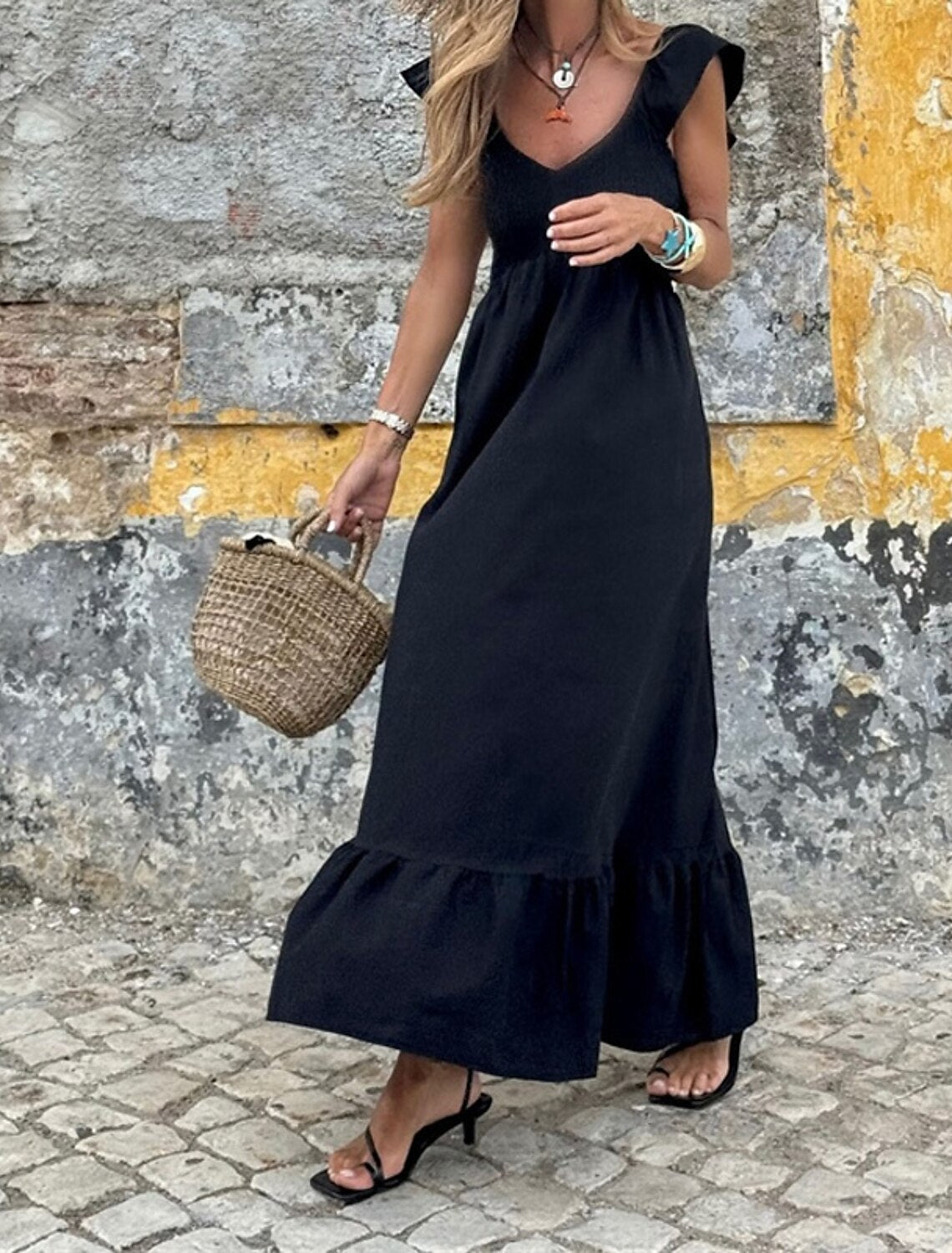 Woman wearing a black V-neck sleeveless maxi dress.