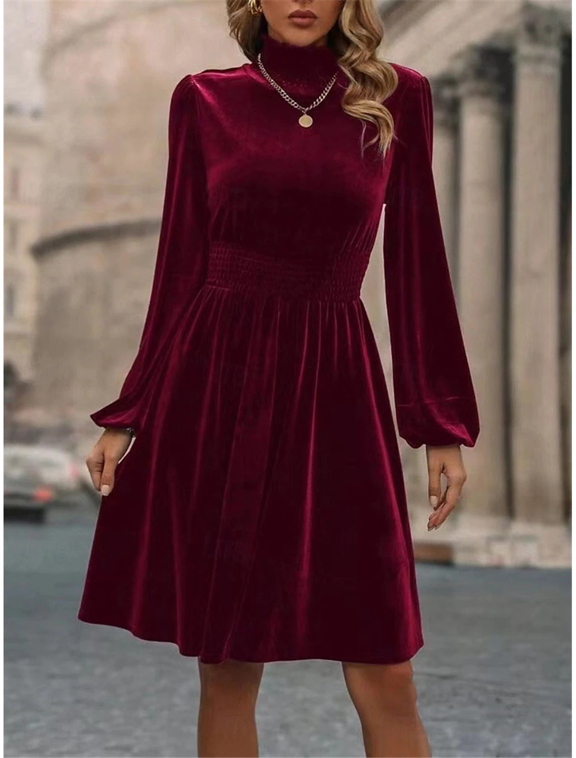 Woman modeling a chic dark ruched velvet mini dress with a turtleneck and long sleeves.