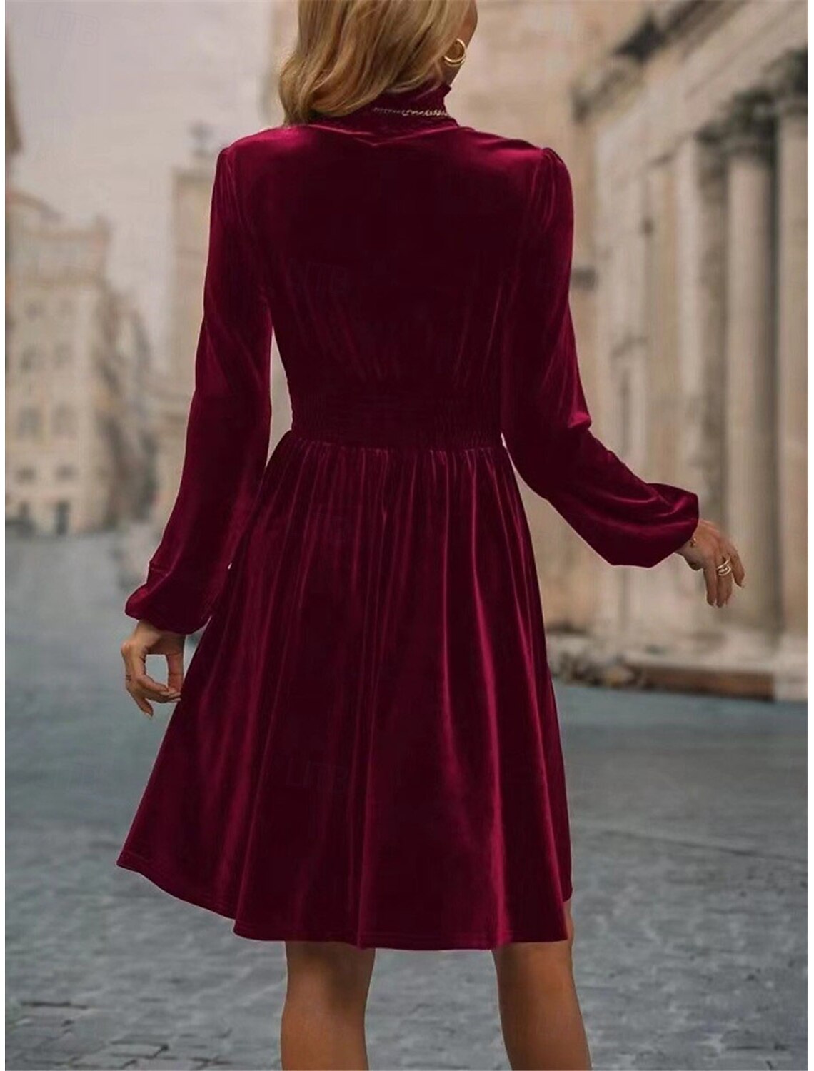 Back view of a woman wearing the elegant dark ruched velvet turtleneck mini dress.