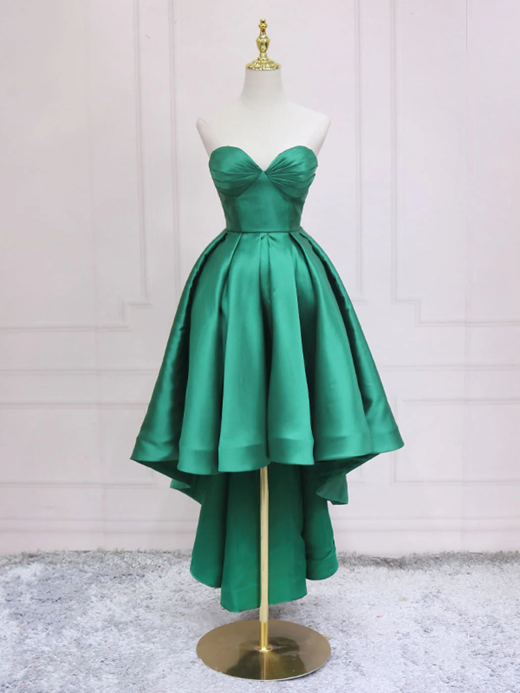 Woman posing in a green sweetheart neck high-low prom dress.