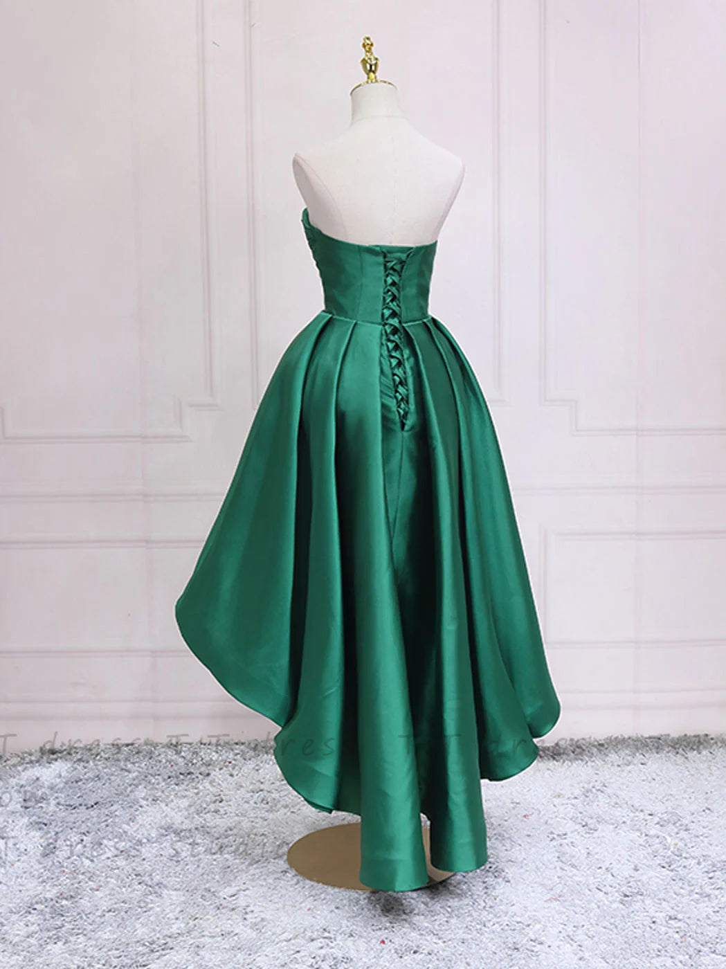Side view of a woman wearing an elegant green high-low homecoming dress.
