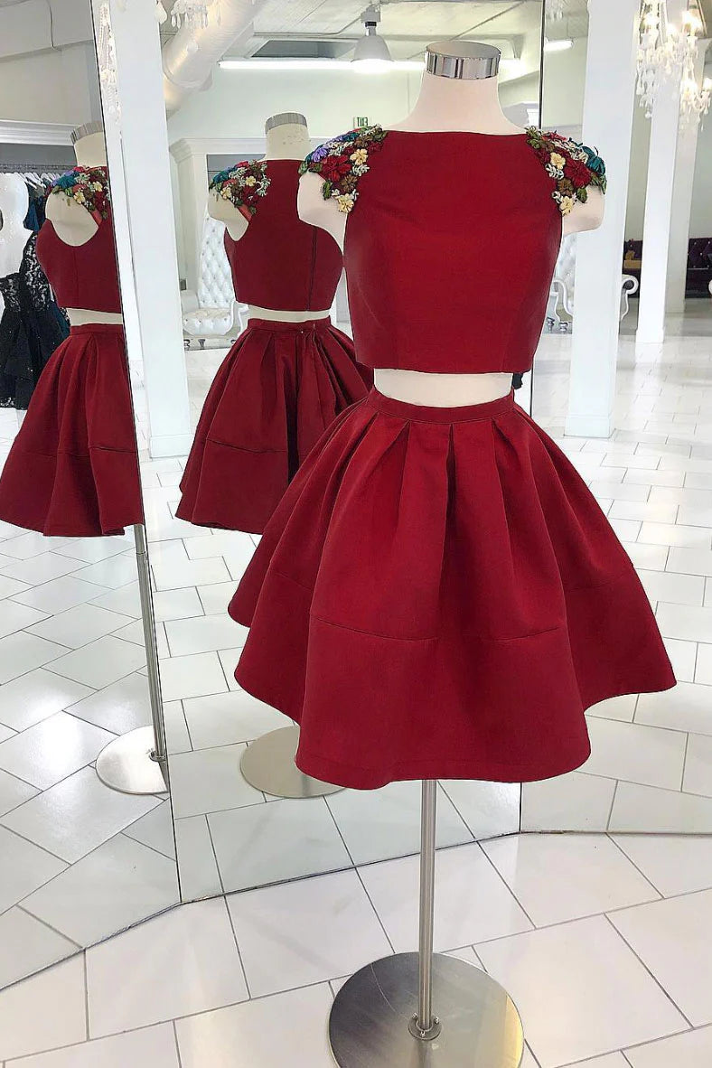 Model wearing a burgundy two-piece satin short prom dress with applique crop top and A-line skirt.
