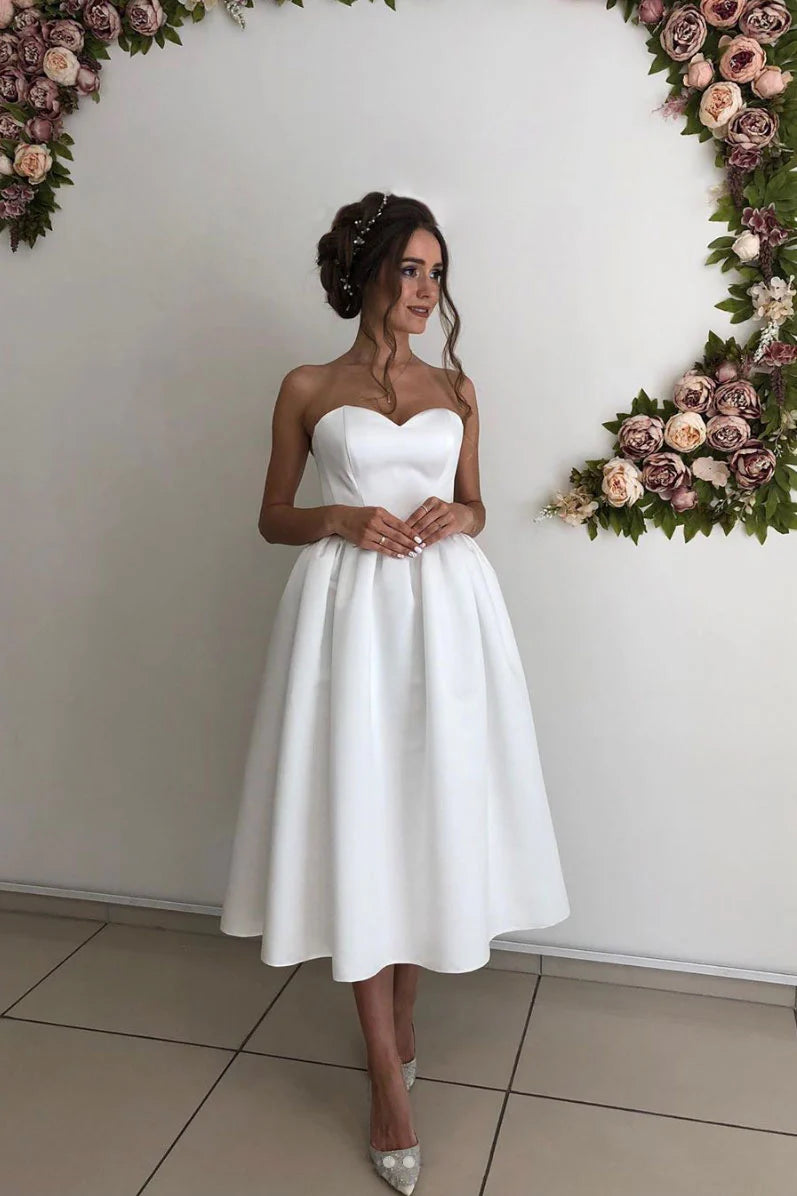 Woman wearing a classic white sweetheart satin short bridesmaid or prom dress.