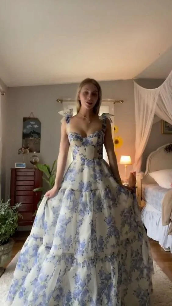Woman wearing a blue floral A-line prom dress with ruffle straps and a tiered skirt.