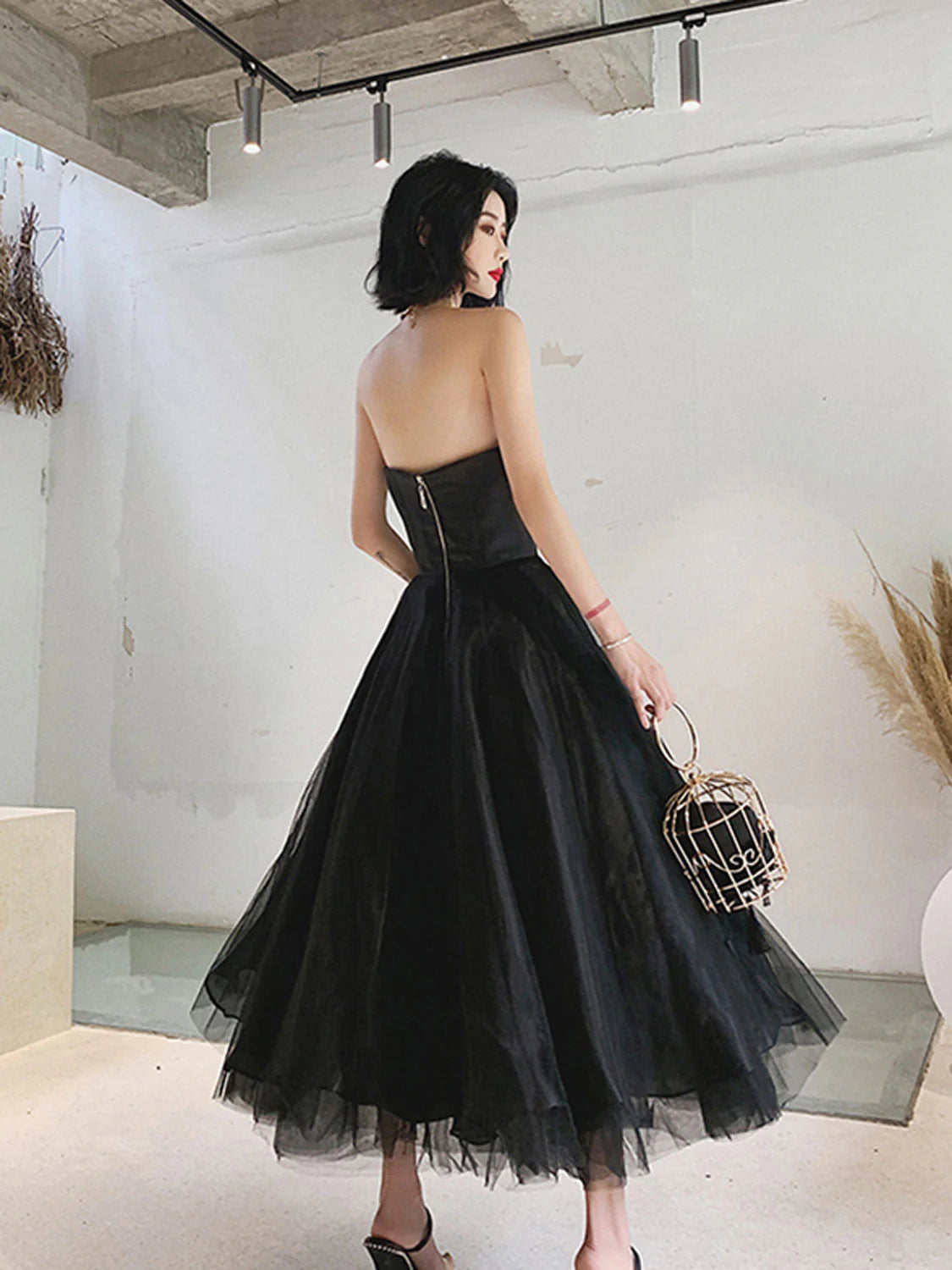 Elegant black tea-length tulle prom dress with A-line silhouette, side view.
