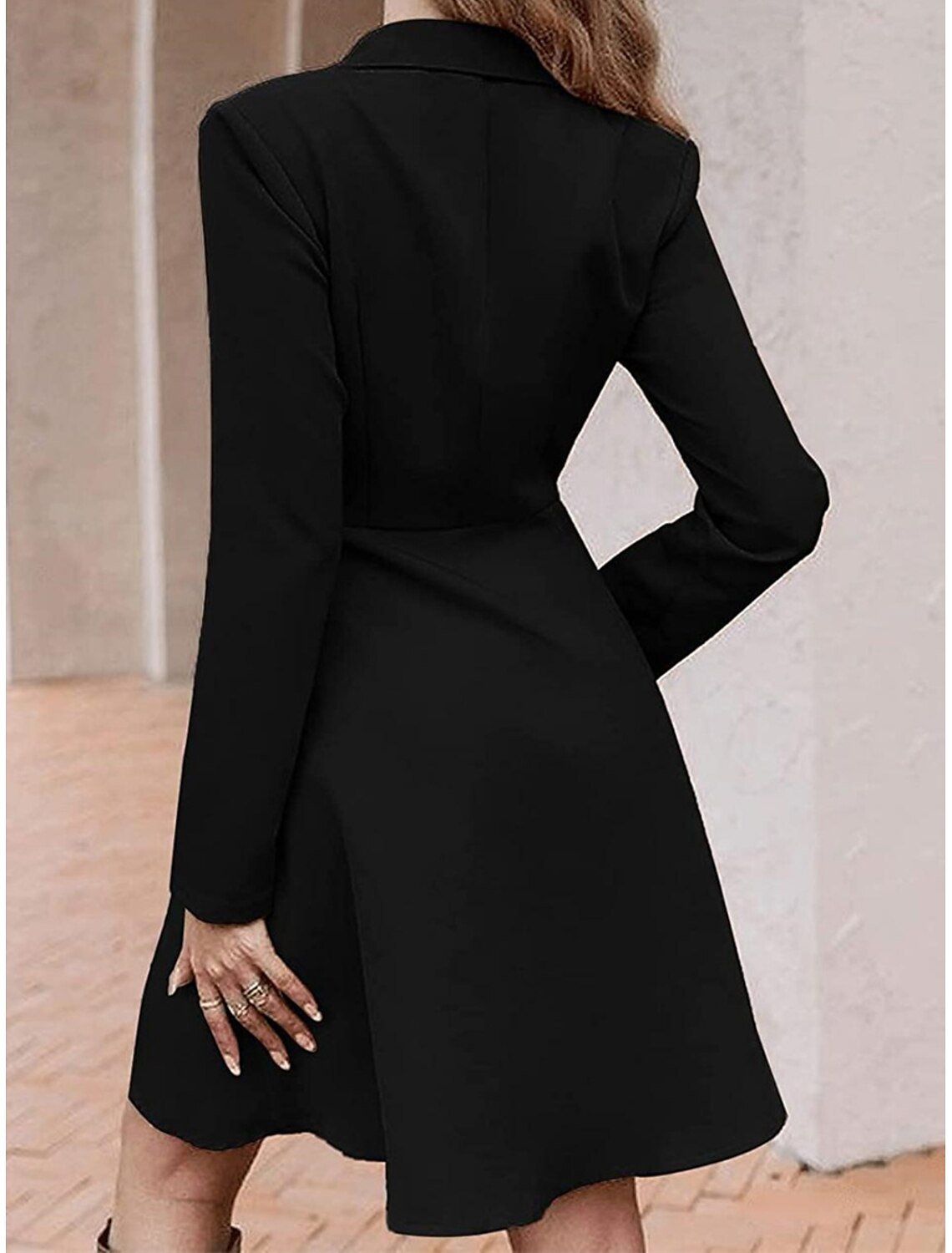 Back view of a woman in a blue long sleeve A-line midi dress.