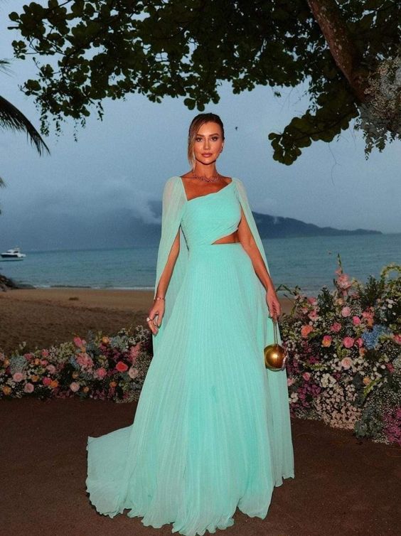 Woman wearing an elegant mint green A-line chiffon prom dress with long cape sleeves.
