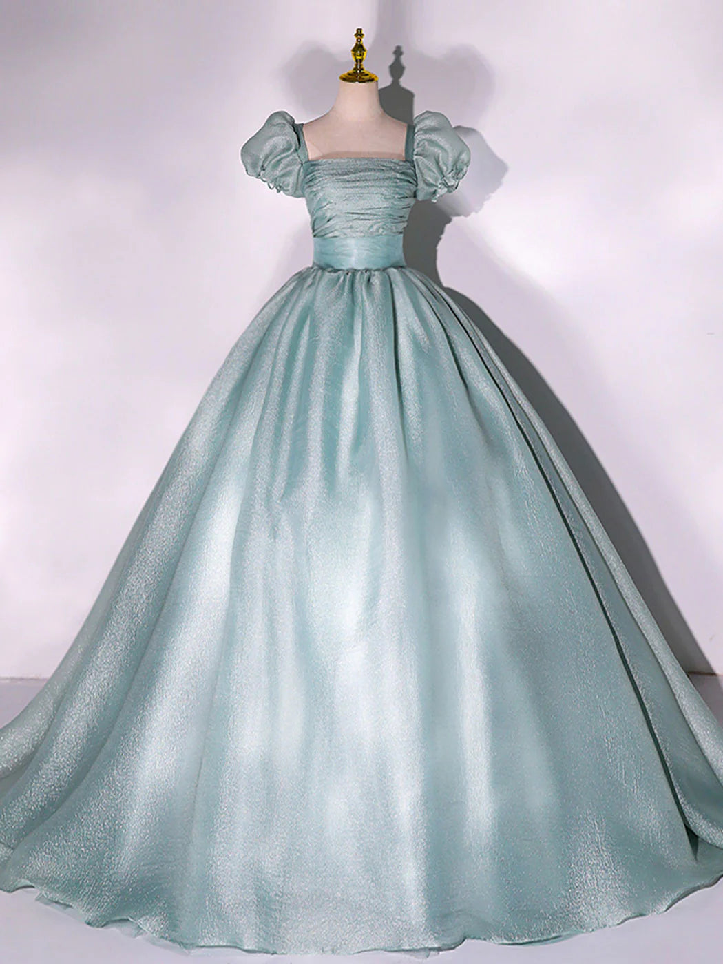 Model wearing an elegant green A-line tulle prom dress with puff sleeves.
