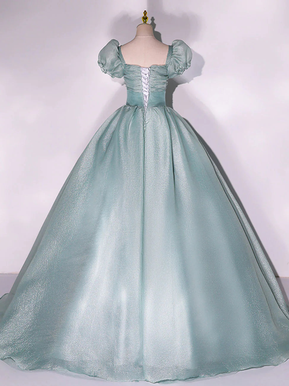 Close-up of the green tulle fabric and puff sleeves on a formal dress.