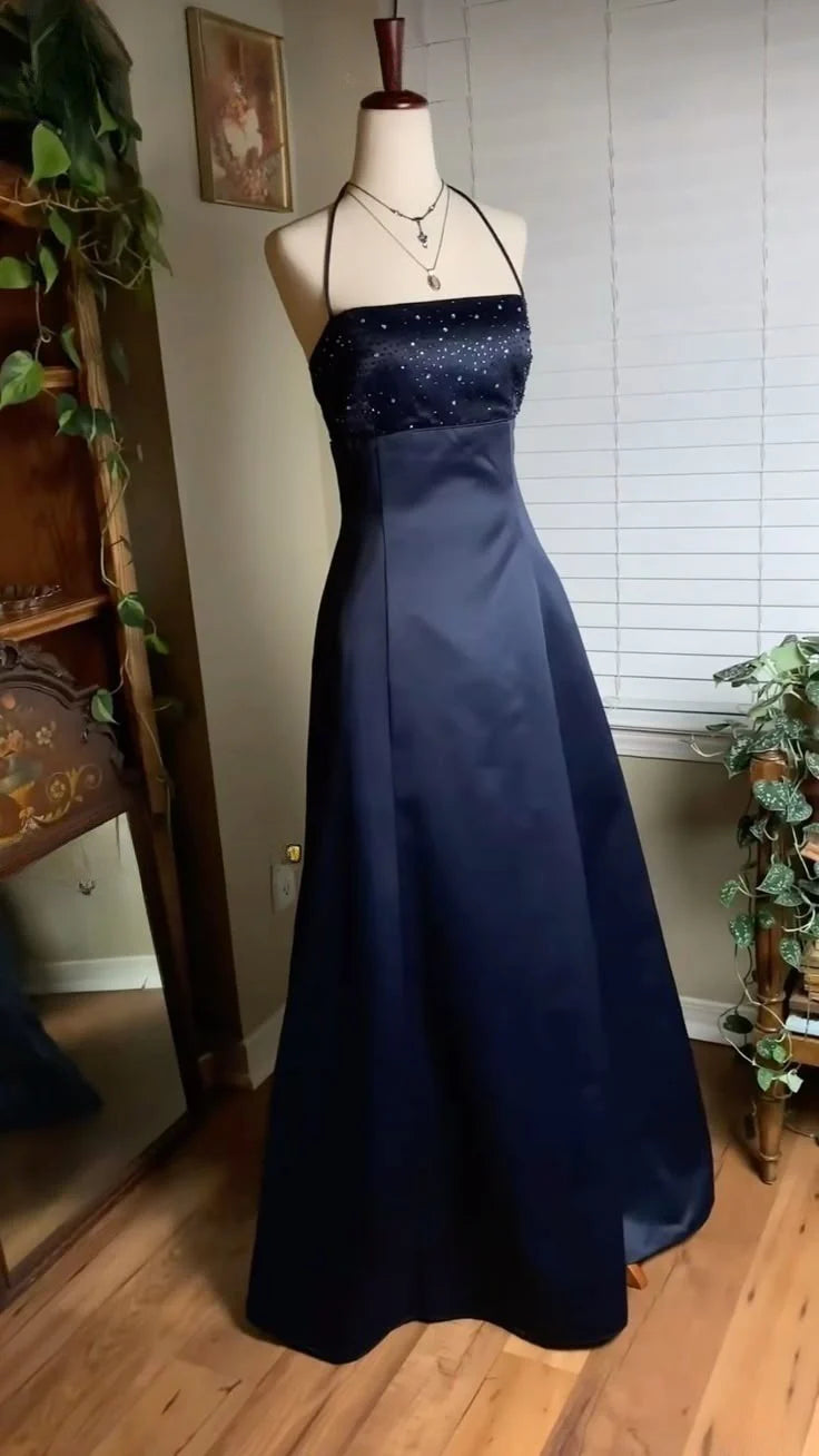Elegant A-Line navy blue prom dress with halter neckline, spaghetti straps, and beaded bodice.