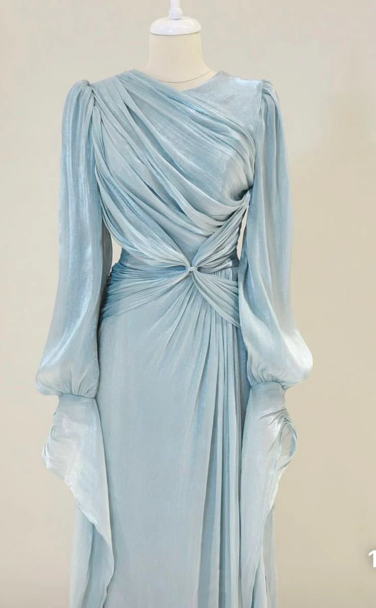 Woman posing in a flowing A-line long sleeve prom gown, showcasing the skirt.