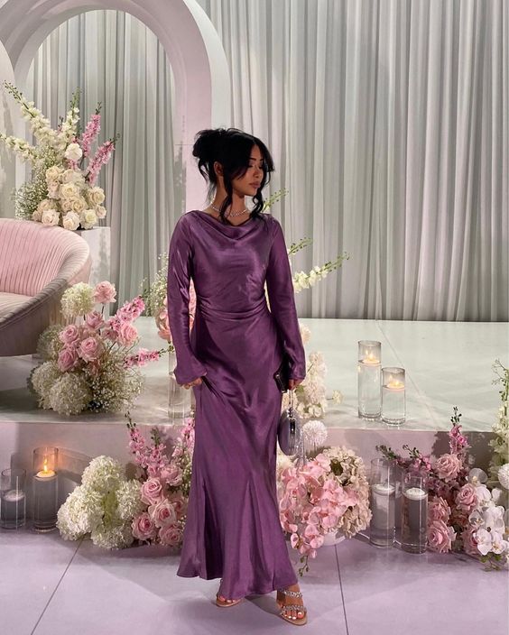 Woman wearing an elegant purple long sleeve satin prom dress.