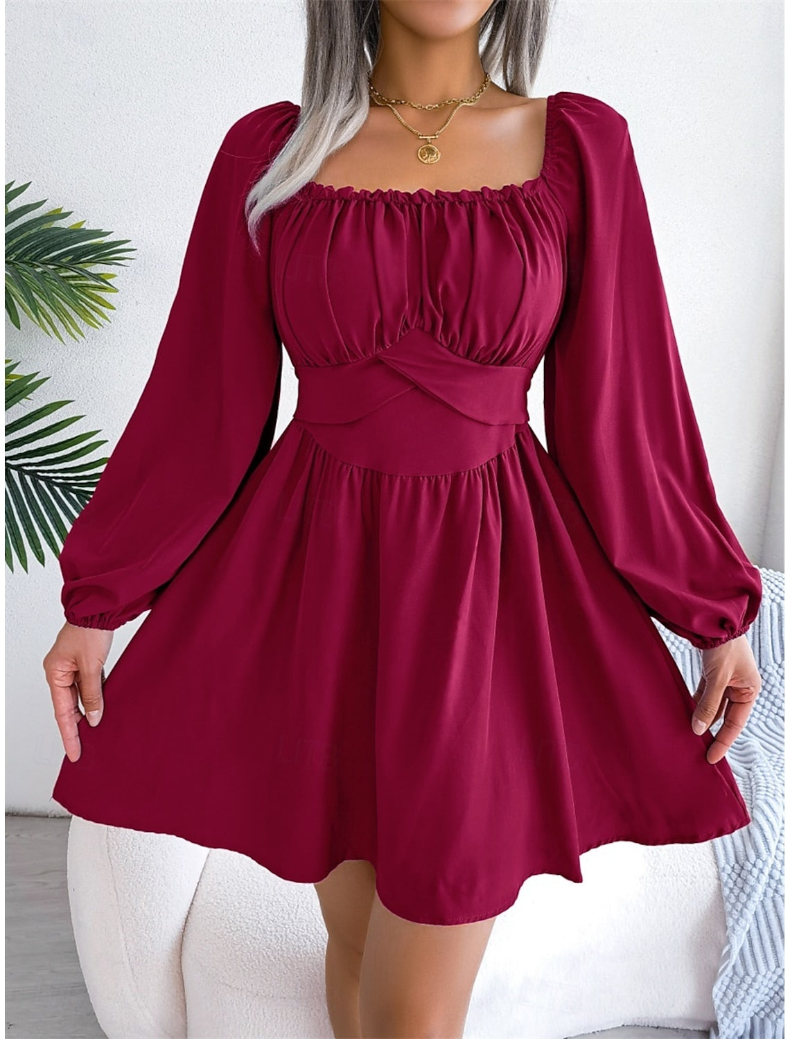 Woman posing in a stylish U-neck mini dress with long lantern sleeves.