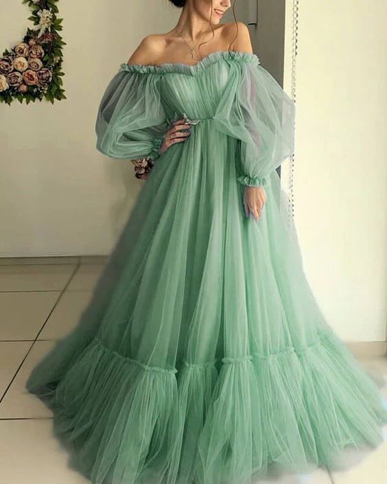 Woman wearing an elegant A-line off-shoulder green tulle floor-length prom dress.