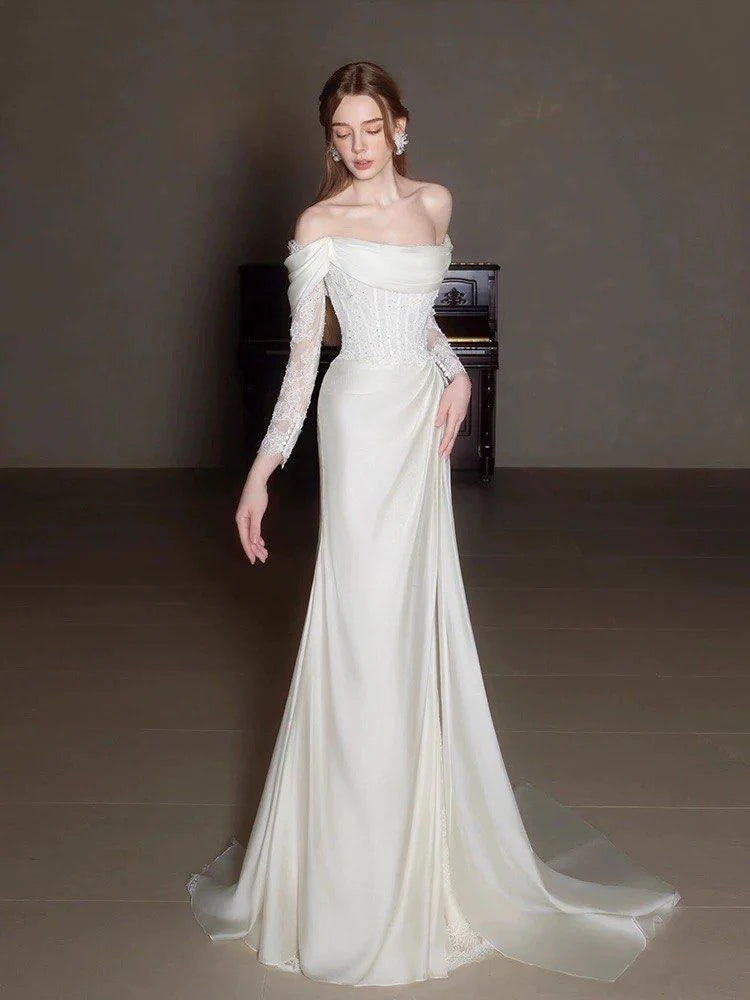 Side view of the A-line off-shoulder lace wedding dress with a flowing train.