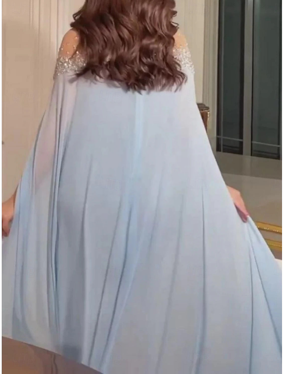 Side view of a woman in a graceful green A-line off-shoulder maxi dress.