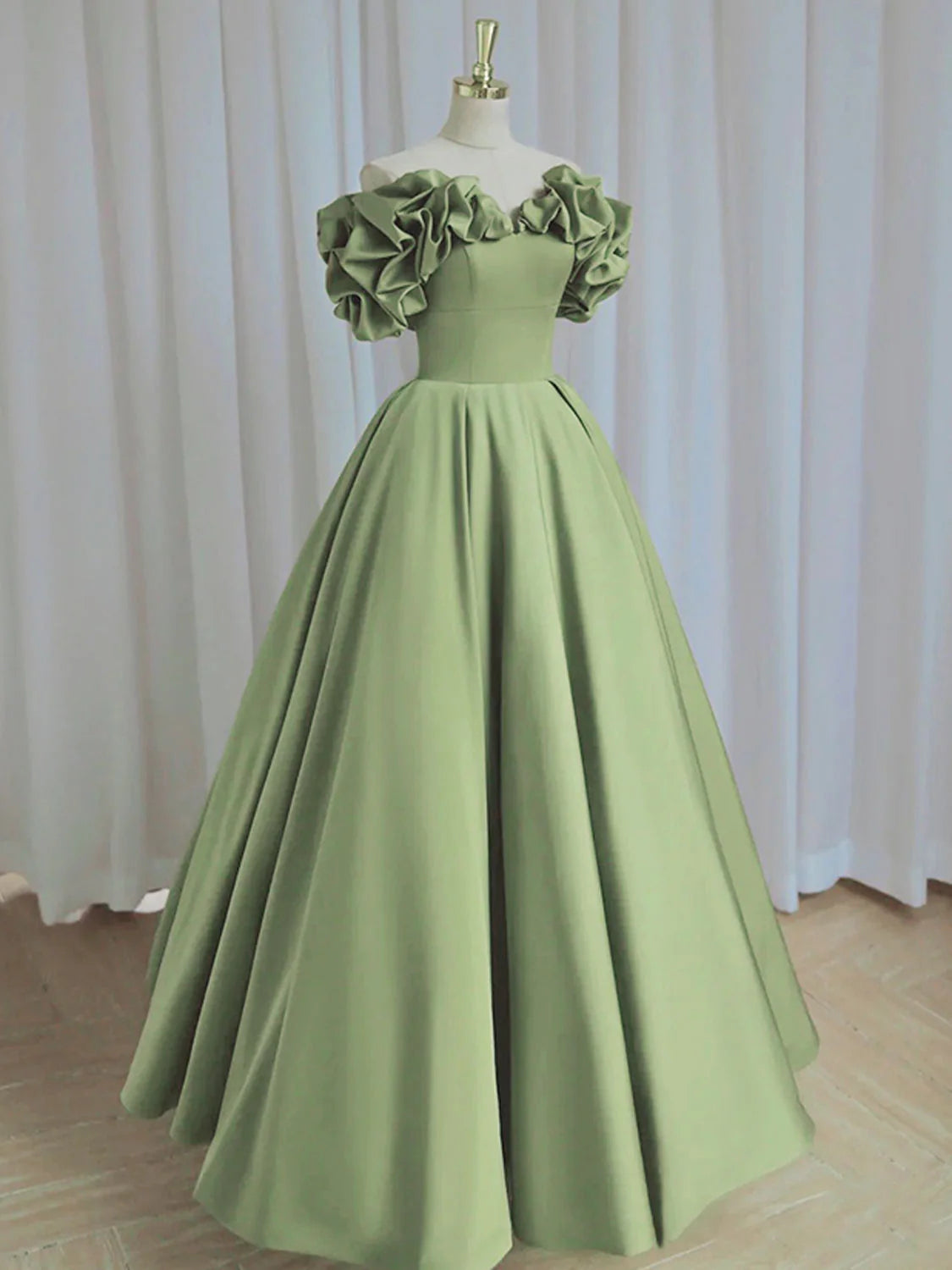 Woman wearing an elegant A-line off-shoulder satin green long prom dress.