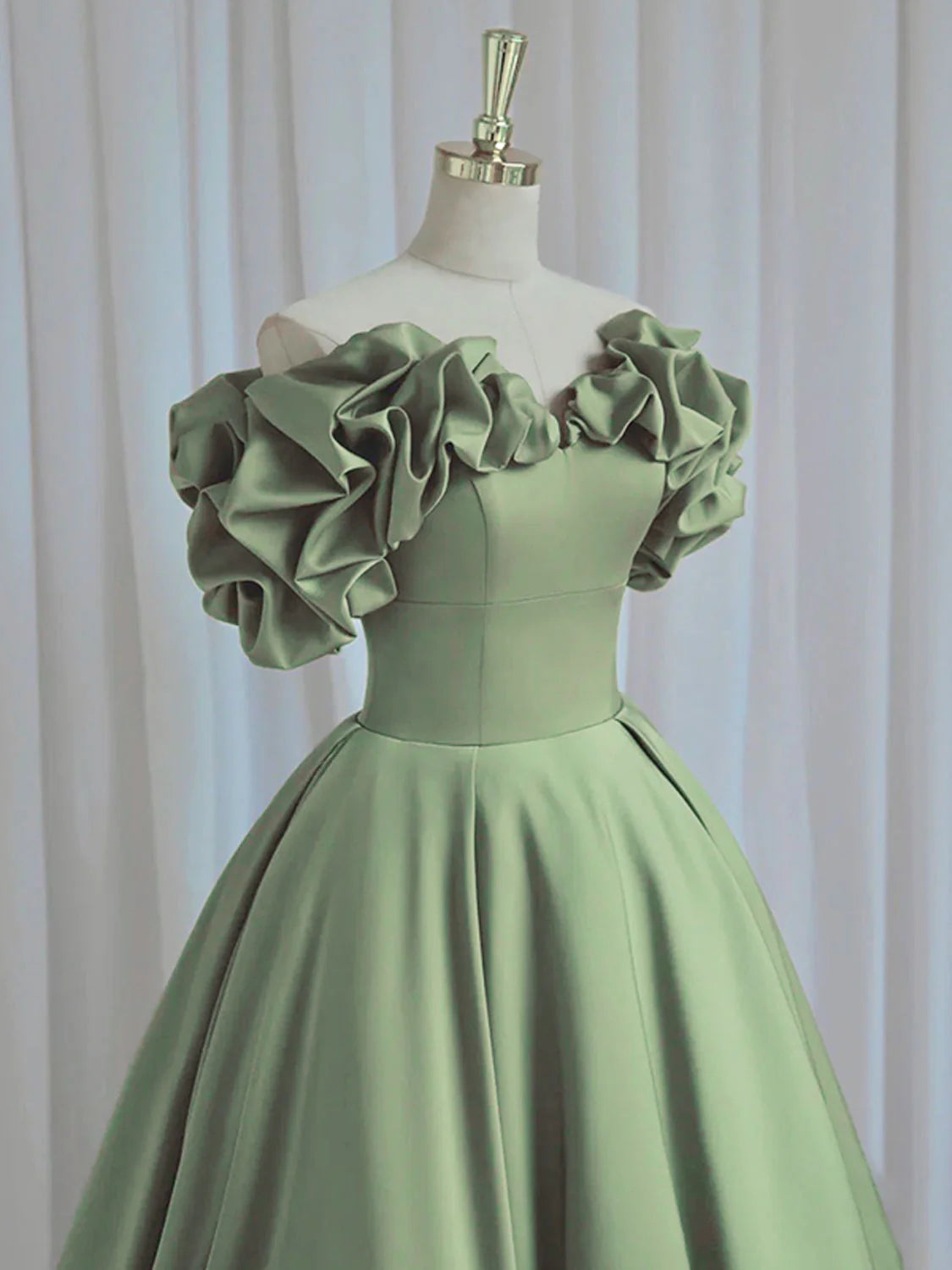 Back view of a woman in a flowing green satin formal gown.