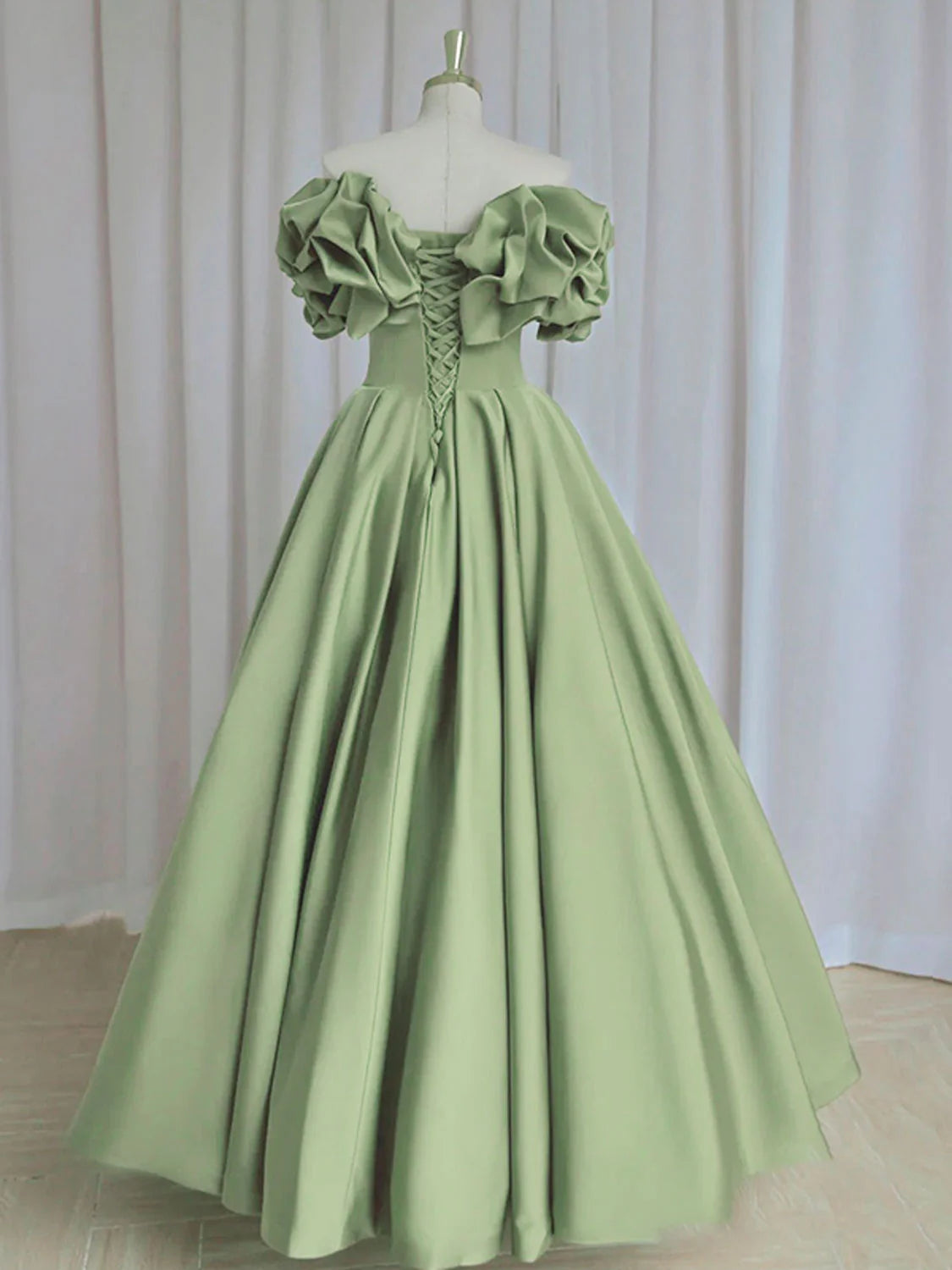 Detail of the luxurious green satin fabric and off-shoulder neckline.