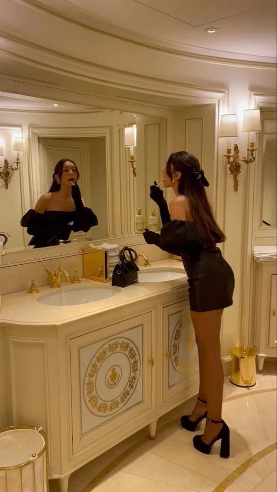 Model wearing a black satin off-the-shoulder A-line homecoming dress, side view.