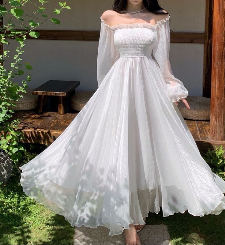 Woman wearing a white off-the-shoulder A-line evening dress, front view.