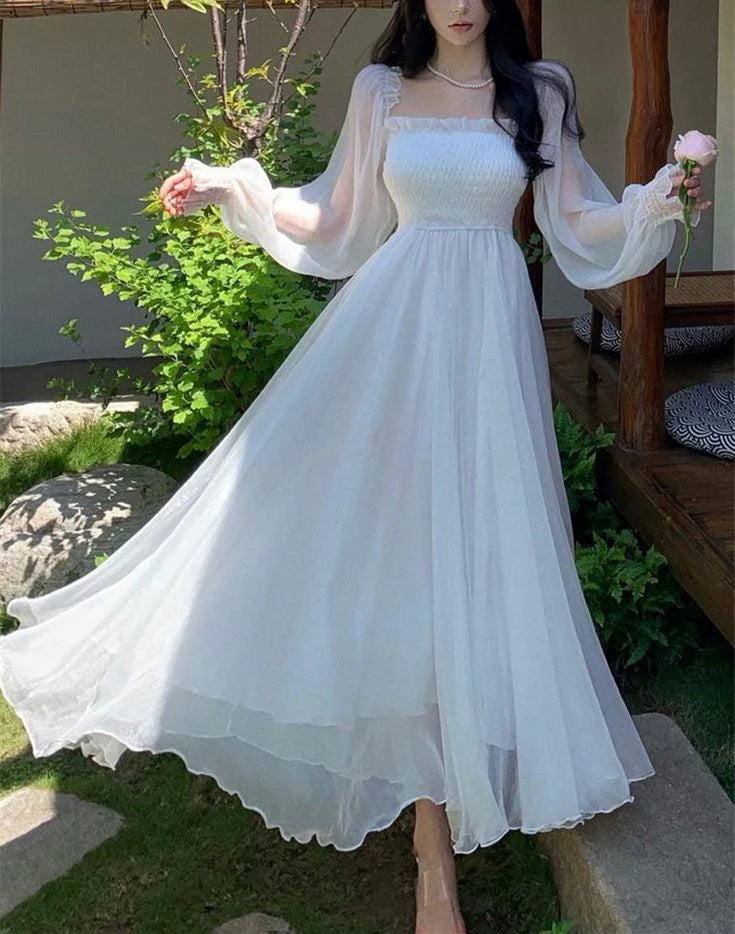 Side view of a woman in a flowing white A-line off-shoulder gown.
