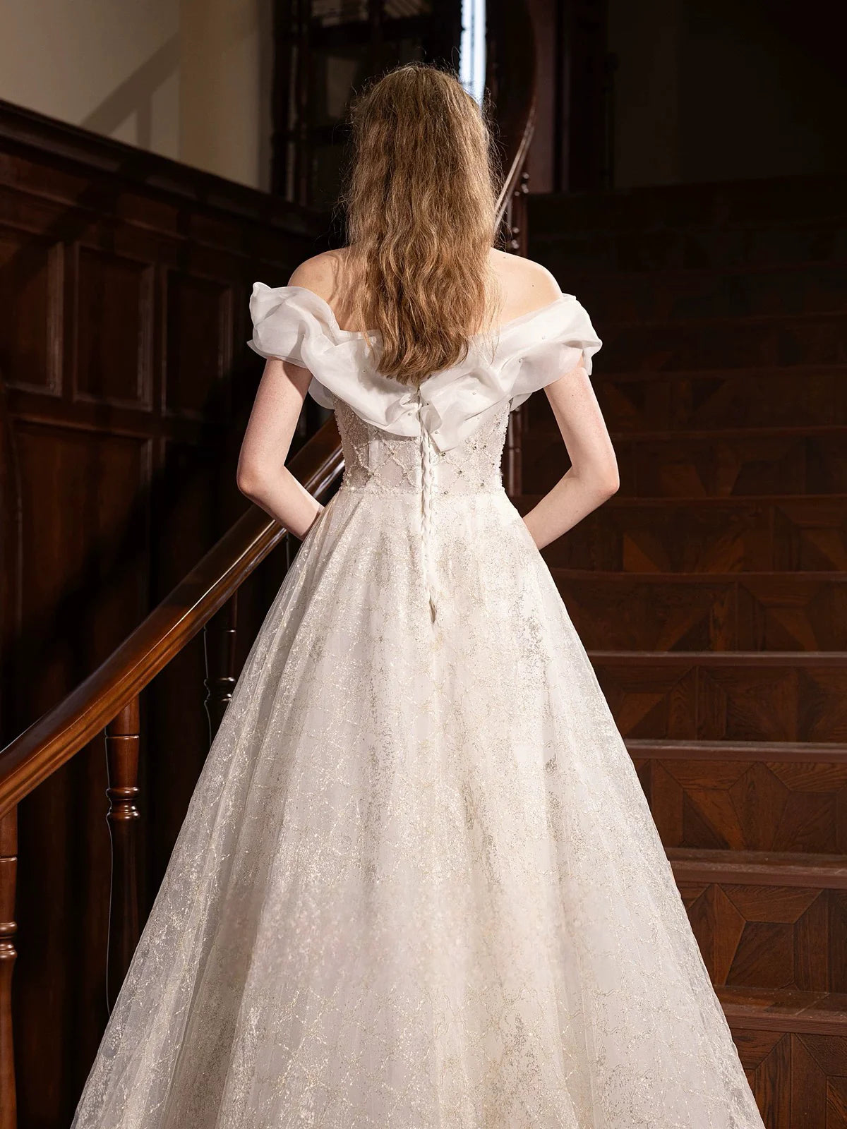 Graceful white A-line off-shoulder long evening dress on a model, side view.
