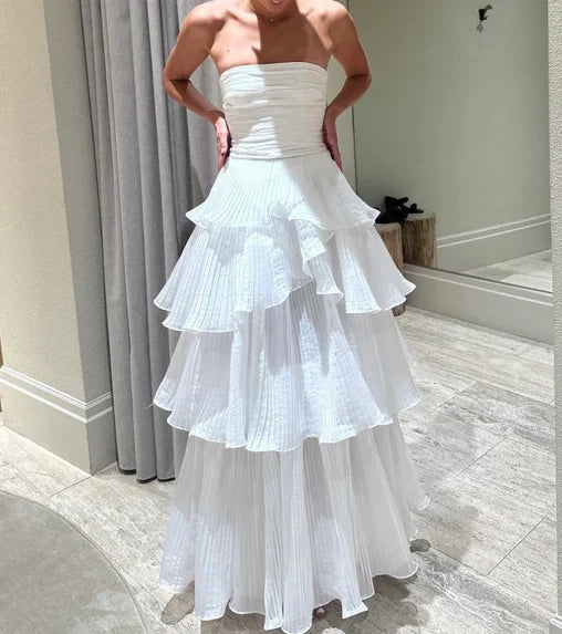 Model wearing an elegant white A-line off-the-shoulder multi-layer long ball gown.