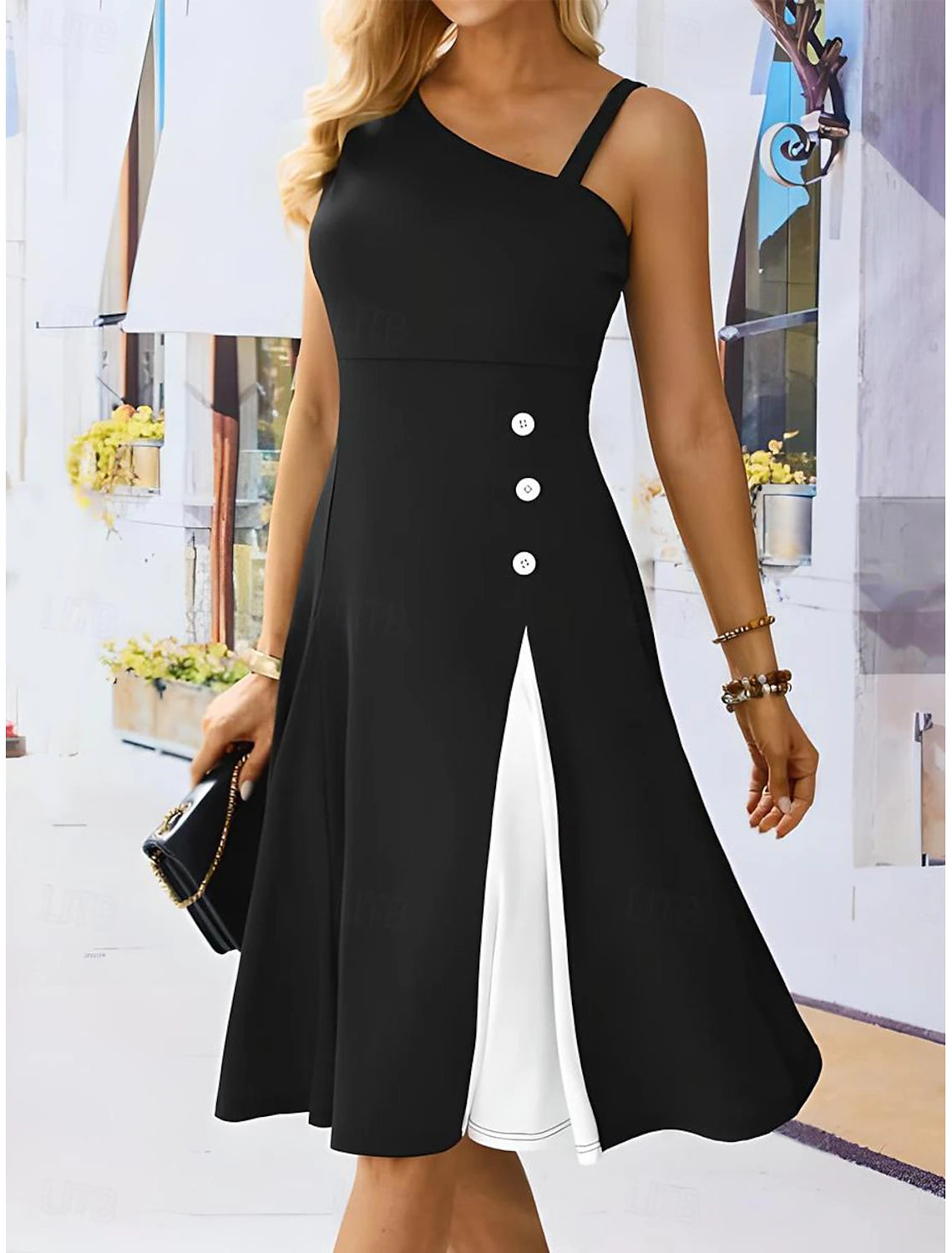 Woman wearing an elegant black and white one-shoulder A-line midi cocktail dress with button detail.