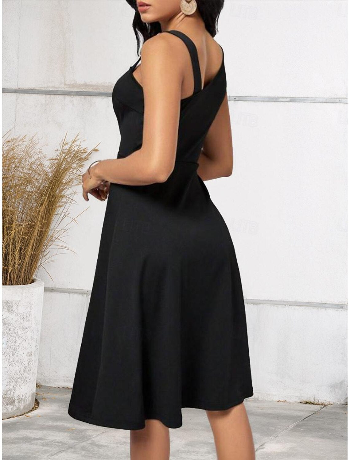 Back view of a woman in a stylish black and white one-shoulder A-line midi dress.